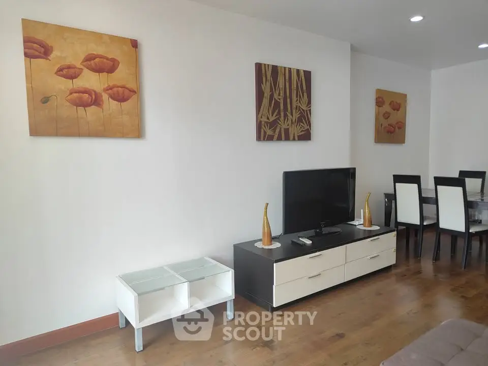 Modern living room with stylish decor and dining area, featuring elegant wall art and sleek furniture.