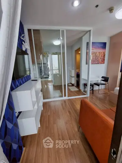 Modern living room with stylish decor and wooden flooring, featuring a TV and open layout.