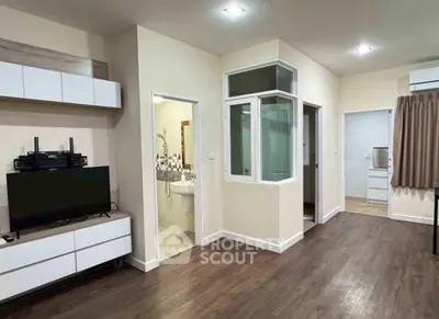 Modern apartment interior with open living area and visible kitchen, featuring sleek flooring and contemporary design.