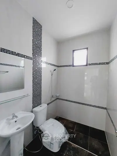 Modern bathroom with sleek design, featuring a toilet, sink, and shower area with stylish tile accents.
