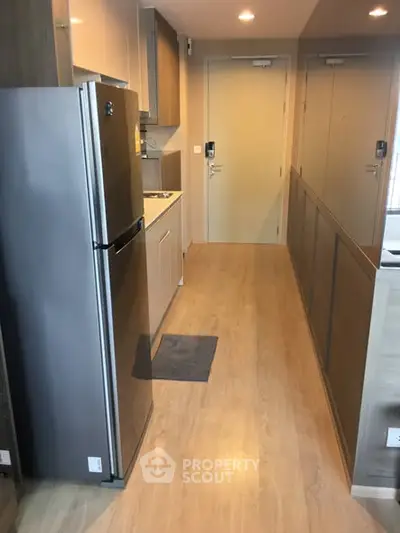 Modern kitchen with sleek design and stainless steel fridge in compact apartment.