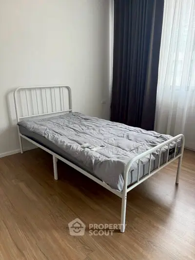 Minimalist bedroom with single metal bed frame and wooden floor