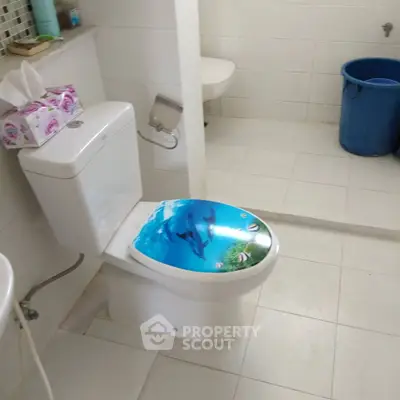 Modern bathroom with unique toilet seat design and white tiled flooring.