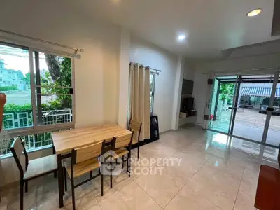 Spacious living room with dining area and large windows overlooking garden.