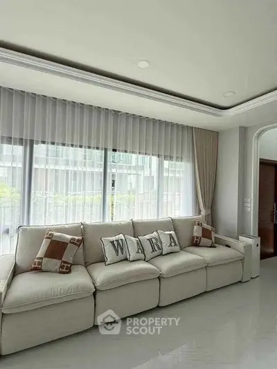 Spacious living room with elegant sofa and large windows in modern apartment.