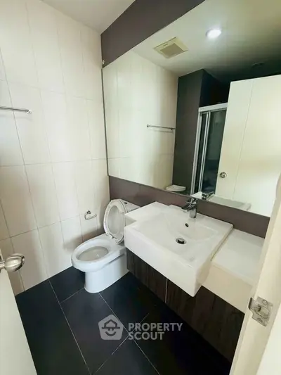 Modern bathroom with sleek design, featuring a large mirror and contemporary fixtures.