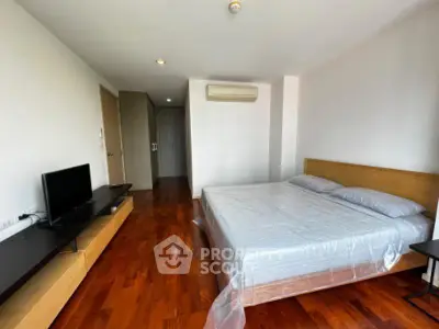 Spacious bedroom with wooden flooring and modern furnishings in a stylish apartment.