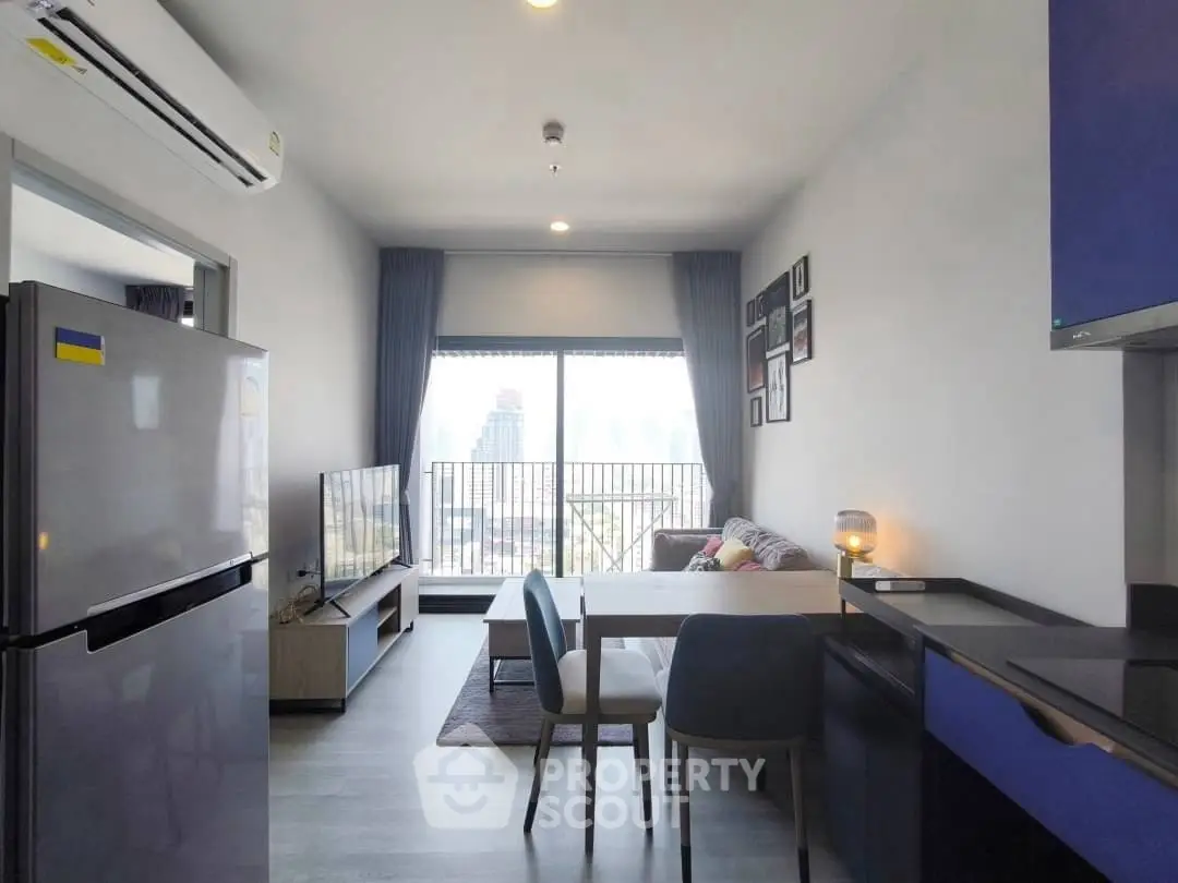Modern living room with city view, stylish furniture, and open kitchen layout in a high-rise apartment.