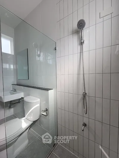 Modern bathroom with sleek shower and toilet in minimalist design.