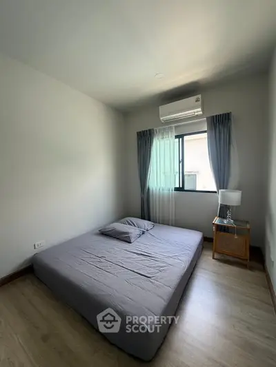 Cozy minimalist bedroom with natural light and modern air conditioning unit.
