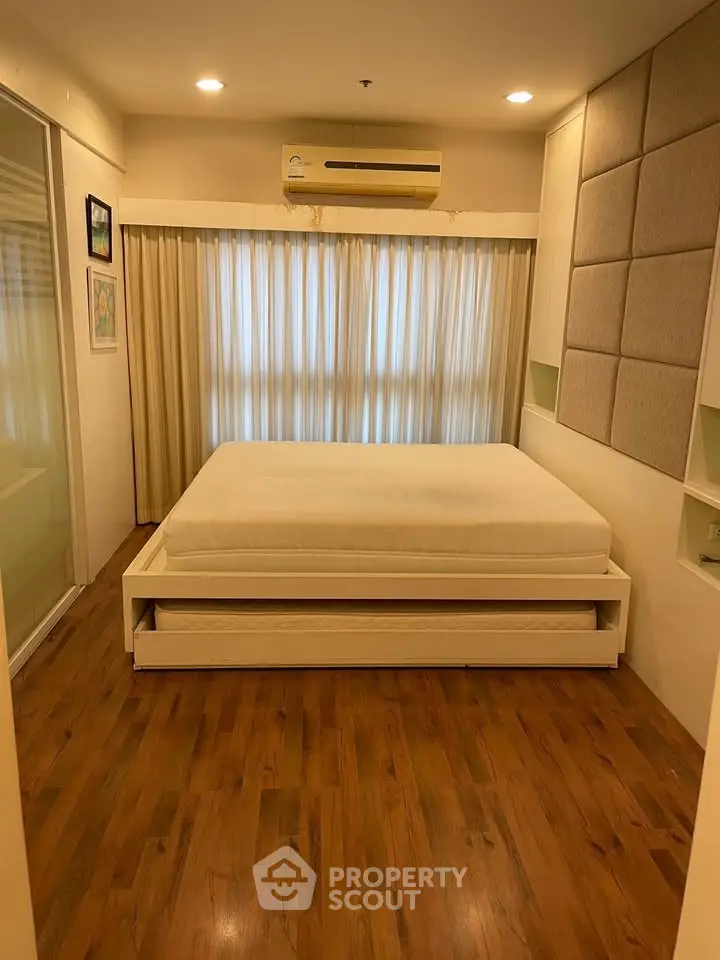 Spacious bedroom with wooden flooring and modern decor, featuring a comfortable bed and ambient lighting.