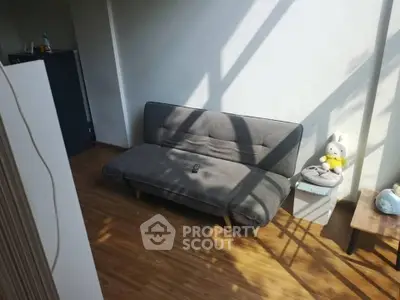 Cozy living room with modern gray sofa and wooden flooring, bathed in natural sunlight.