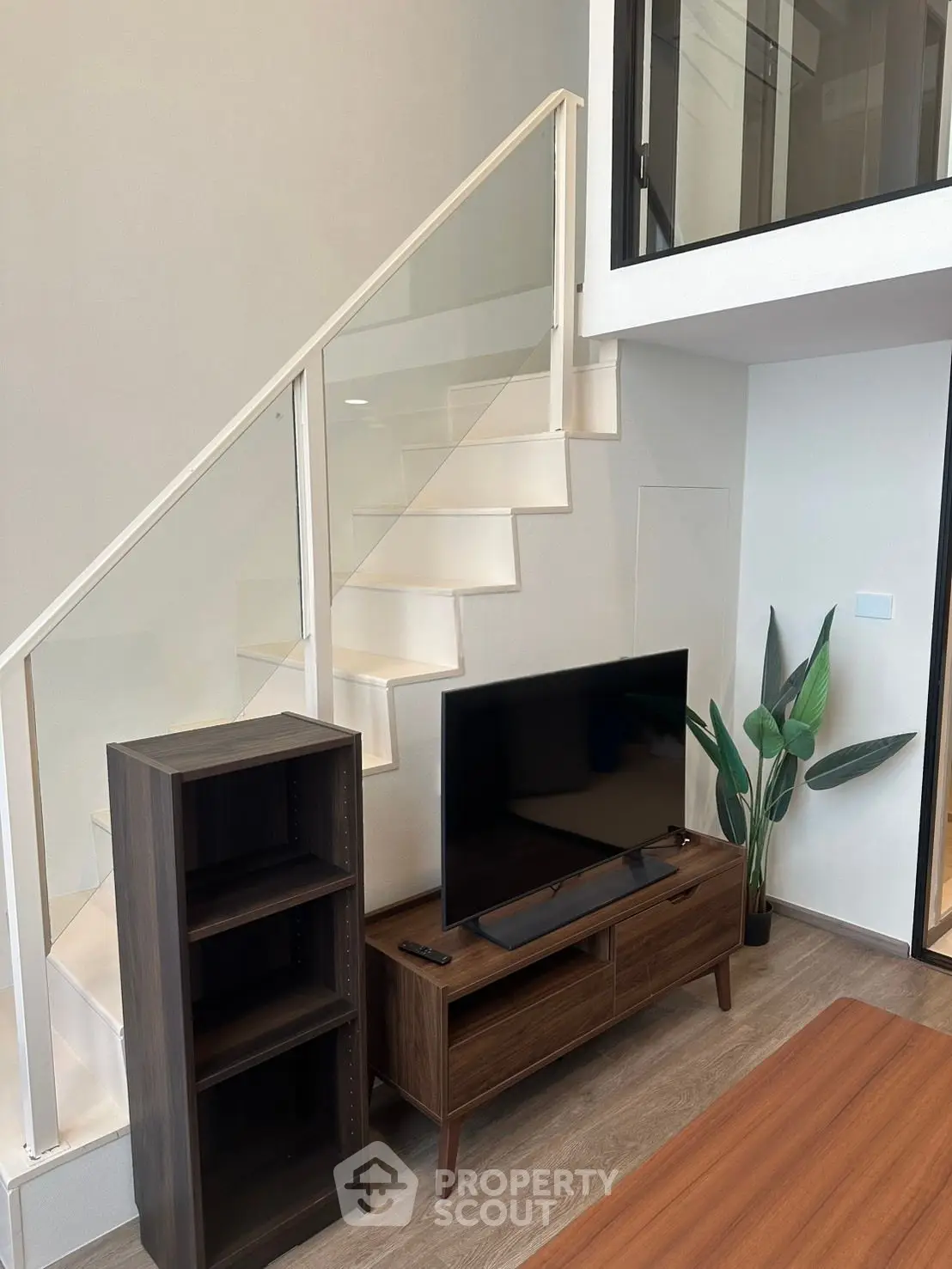 Modern living room with stylish staircase and sleek TV stand, perfect for contemporary urban living.