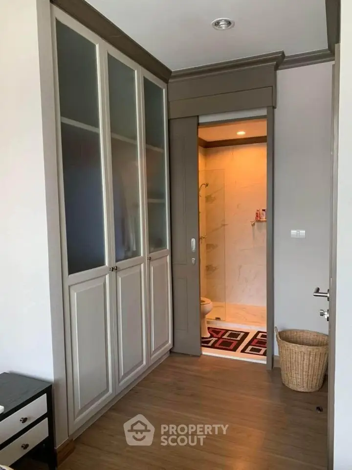 Modern interior with built-in wardrobe and bathroom entrance, featuring sleek design and warm lighting.