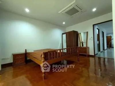 Spacious bedroom with wooden flooring and classic furniture in a modern apartment.