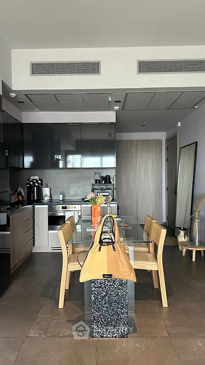 Modern kitchen with sleek cabinetry and dining area featuring stylish wooden chairs and table.