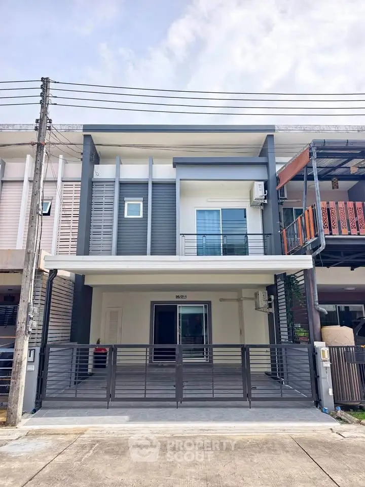 Modern two-story townhouse with sleek facade and spacious driveway in a suburban neighborhood.