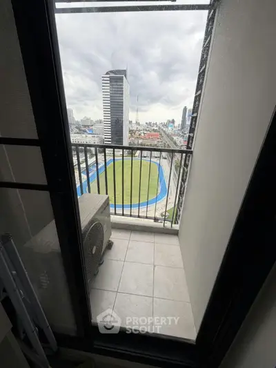Stunning city view from a high-rise balcony overlooking a sports field and skyline.