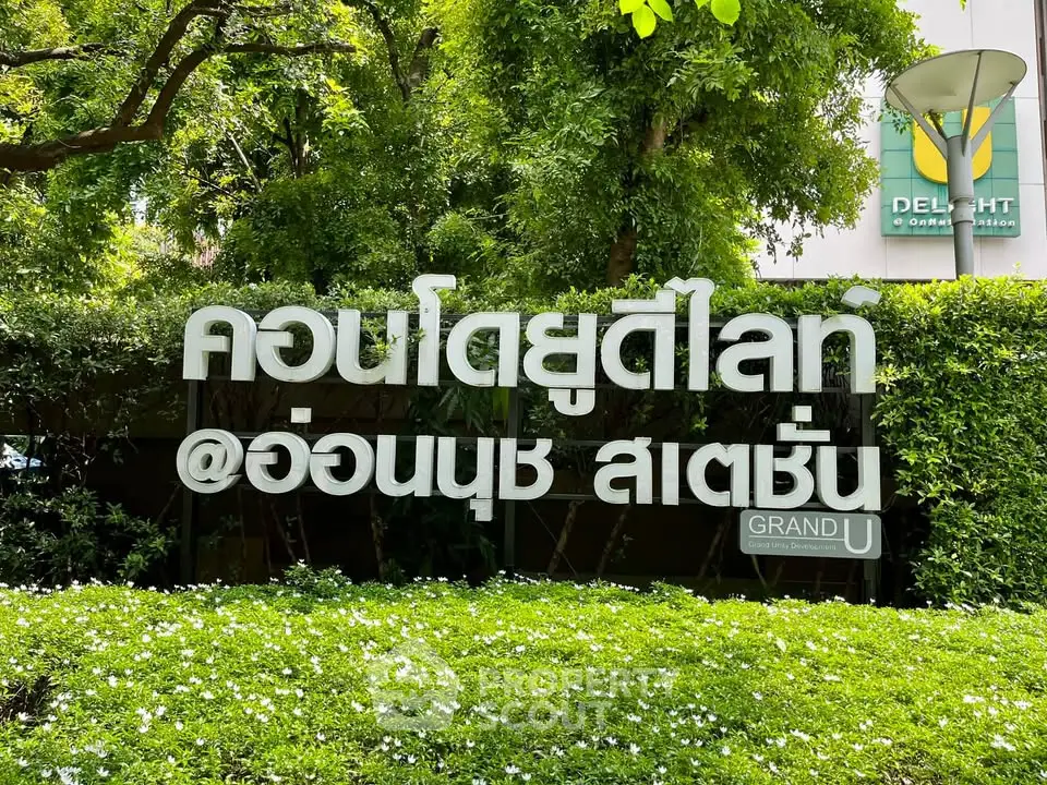 Lush green garden with modern building signage at Grand U Delight Onnut Station.