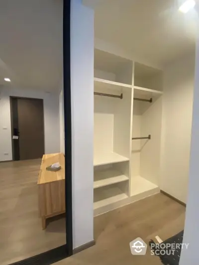 Spacious modern walk-in closet with wooden flooring and ample storage space.