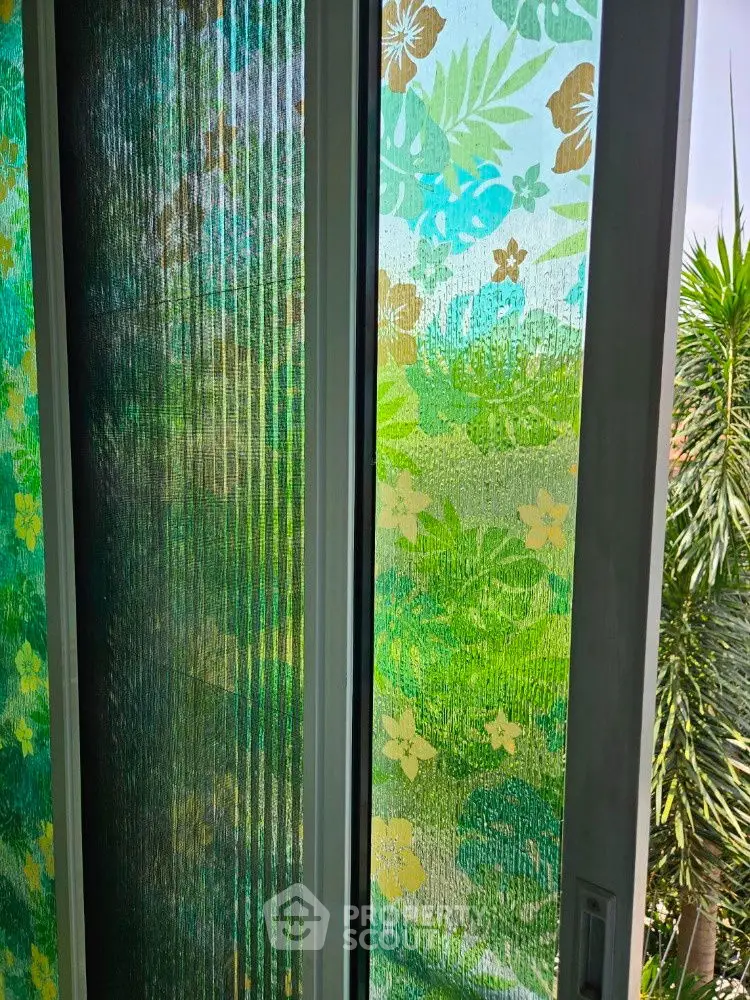Vibrant floral-patterned glass window with lush garden view, perfect for serene living spaces.
