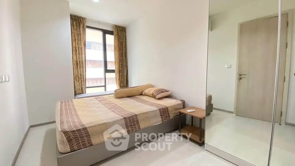 Modern bedroom with large window and stylish decor in a contemporary apartment.