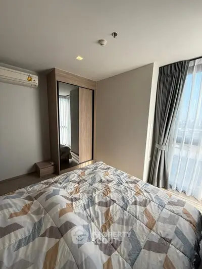 Modern bedroom with large window and stylish decor in a high-rise apartment.