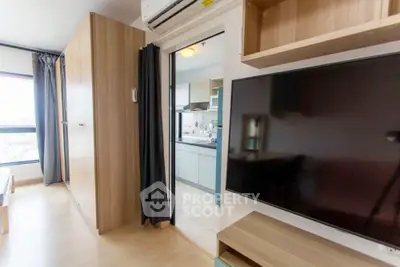 Modern apartment interior with open kitchen and living area, featuring sleek wooden furniture and large TV.