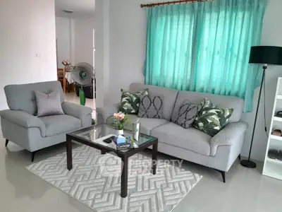 Stylish living room with modern gray sofa set and glass coffee table, accented by green curtains and a patterned rug.