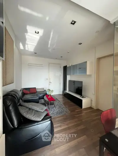 Modern living room with sleek black leather sofas and wall-mounted TV unit.