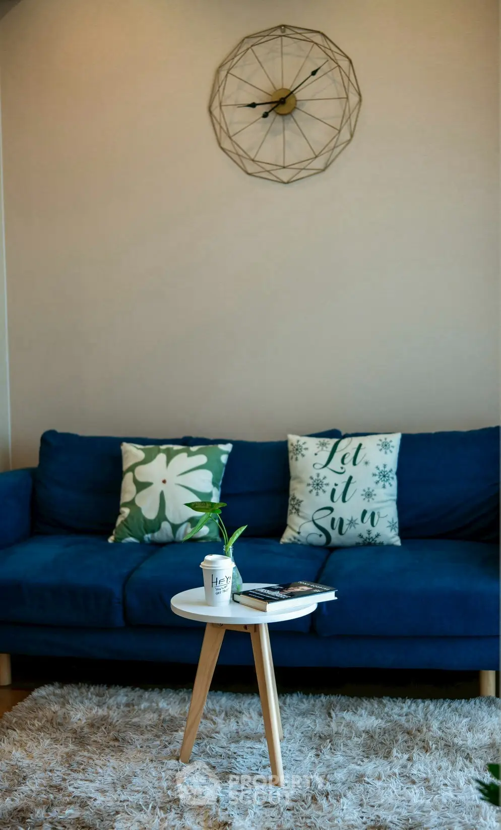 Cozy living room with blue sofa, stylish decor, and modern wall clock.