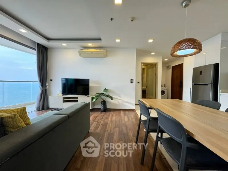 Modern living room with ocean view, sleek furniture, and open layout in luxury apartment.