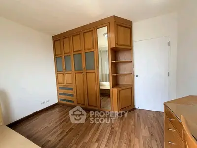 Spacious bedroom with elegant wooden wardrobe and hardwood flooring