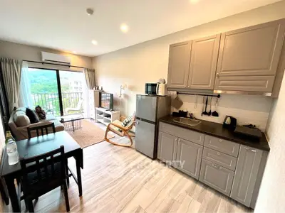 Modern open-plan living room with kitchen, featuring stylish cabinetry and scenic balcony view.