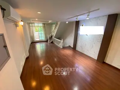 Spacious living room with wooden flooring and modern lighting in a stylish home.
