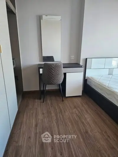 Modern bedroom with sleek furniture and wooden flooring, featuring a stylish desk and chair.
