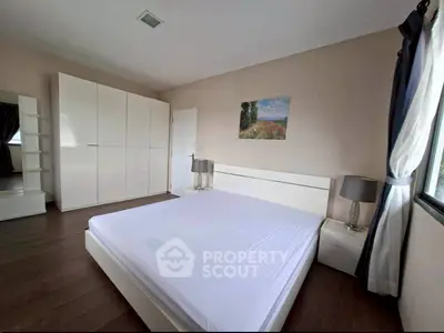 Spacious bedroom with modern white furniture and large window for natural light.