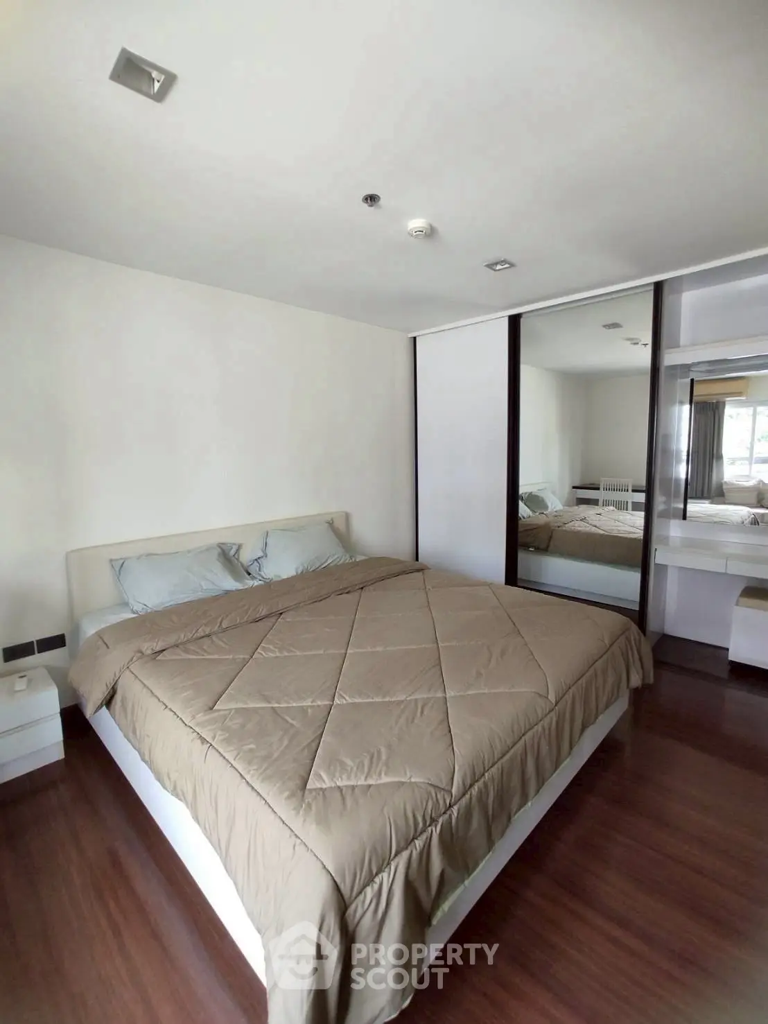 Modern bedroom with mirrored wardrobe and cozy bedding in a stylish apartment.