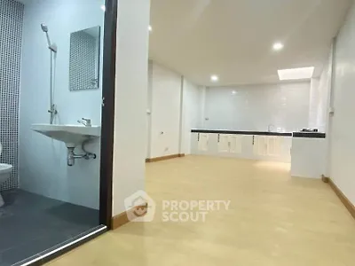 Spacious open-plan living area with adjacent modern bathroom and sleek kitchen.