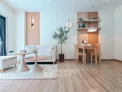 Modern living room with stylish furniture and dining area, featuring wooden flooring and elegant lighting.