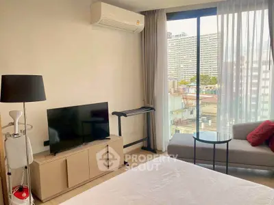 Modern bedroom with city view, featuring a cozy sofa, TV, and air conditioning.