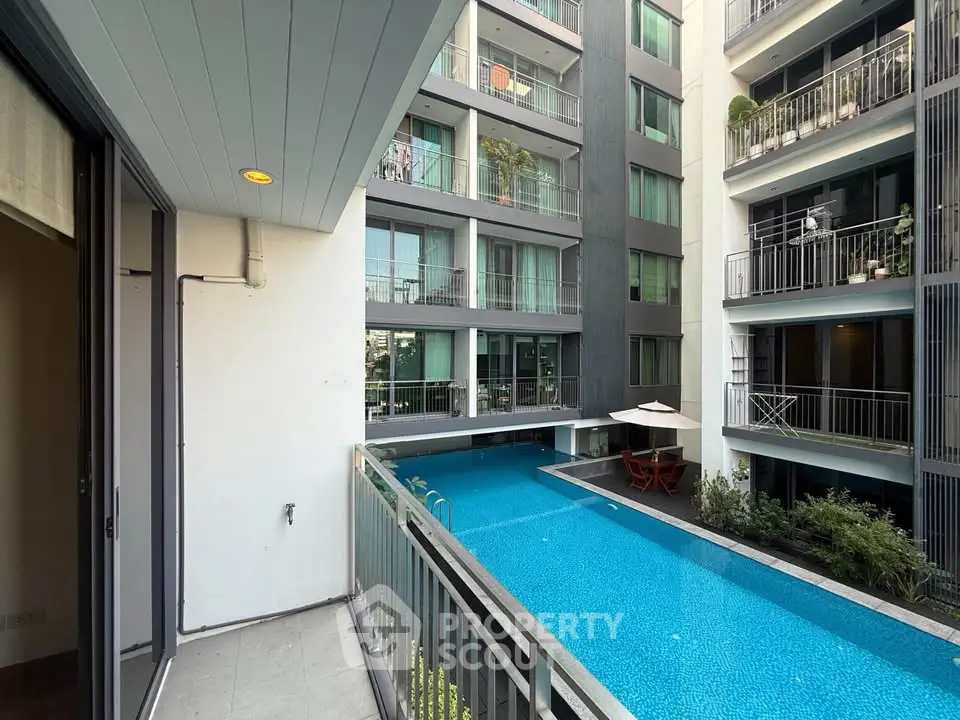 Modern apartment balcony overlooking a serene pool in a stylish residential complex.