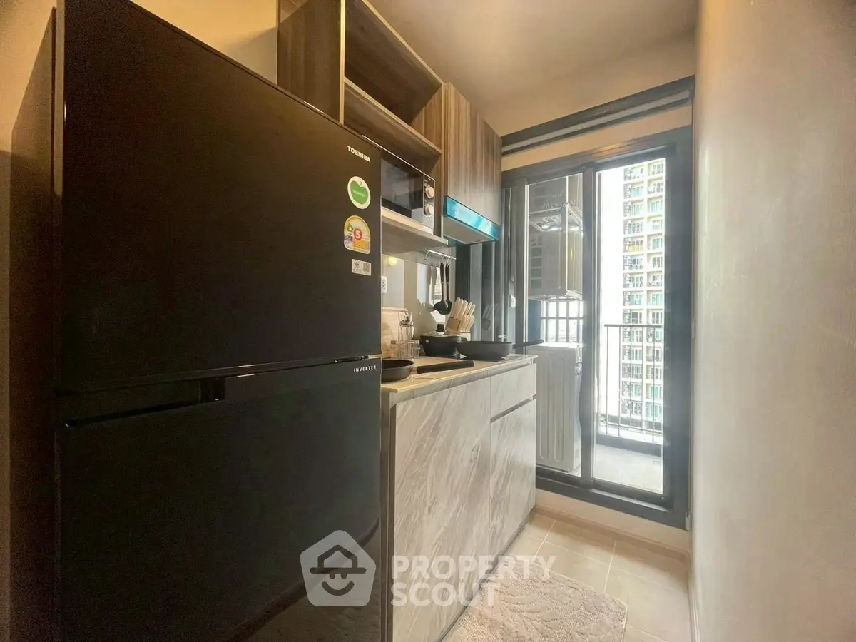 Modern compact kitchen with balcony view in urban apartment