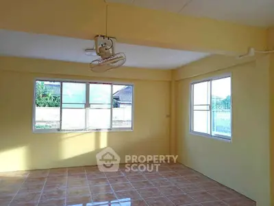 Spacious sunlit room with tiled flooring and ceiling fan, perfect for versatile living space.