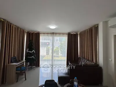Spacious living room with large windows and garden view, featuring a cozy corner sofa and a Christmas tree.