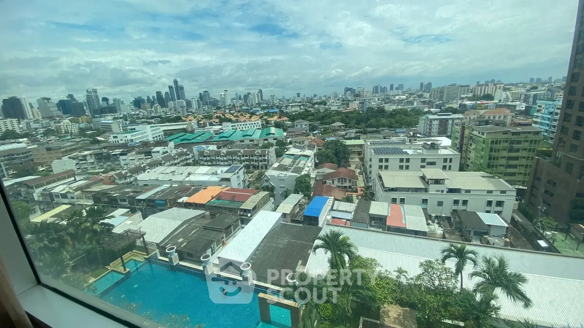 Stunning cityscape view from high-rise window overlooking urban skyline and pool area.