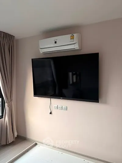 Modern living room with wall-mounted TV and air conditioning unit, perfect for comfortable living.