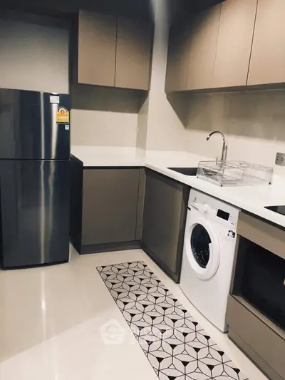 Modern kitchen with sleek cabinets, fridge, washing machine, and oven in a stylish apartment.