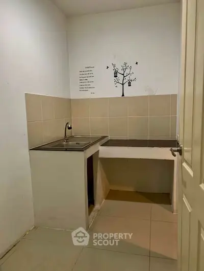 Compact kitchen area with tiled backsplash and stainless steel sink, ideal for small apartments.