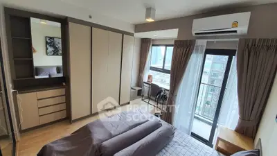 Modern bedroom with city view, featuring sleek furniture and large windows for natural light.